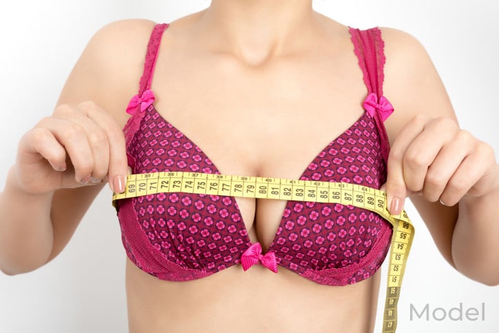 close up of woman's breast wwhile she holds measuring tape